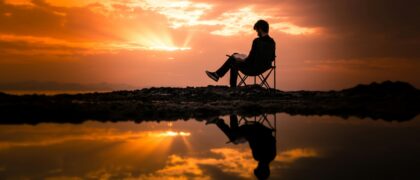 Someone in a chair reading a book as the sun sets